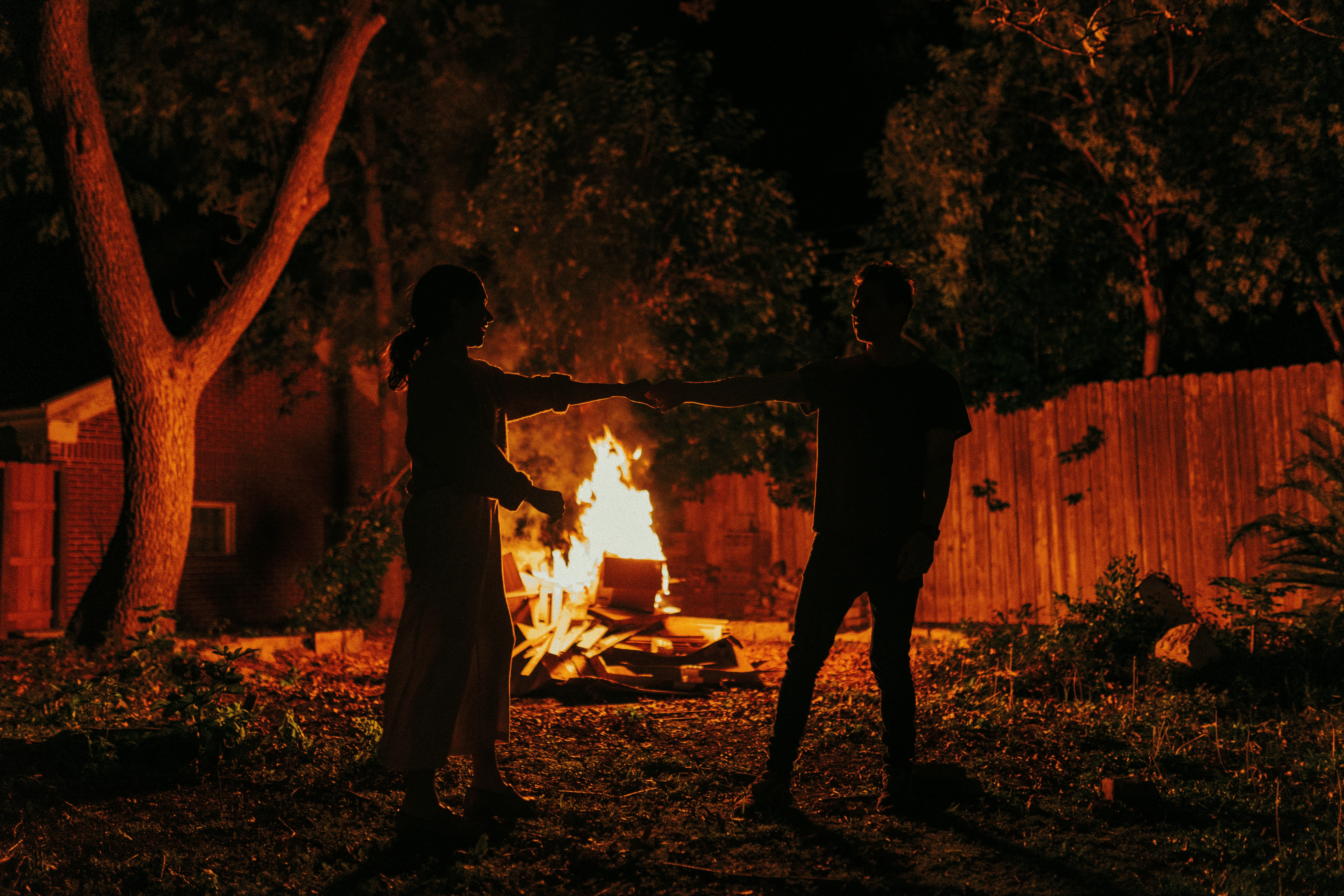 silhouette of 2 men standing near bonfire during night time